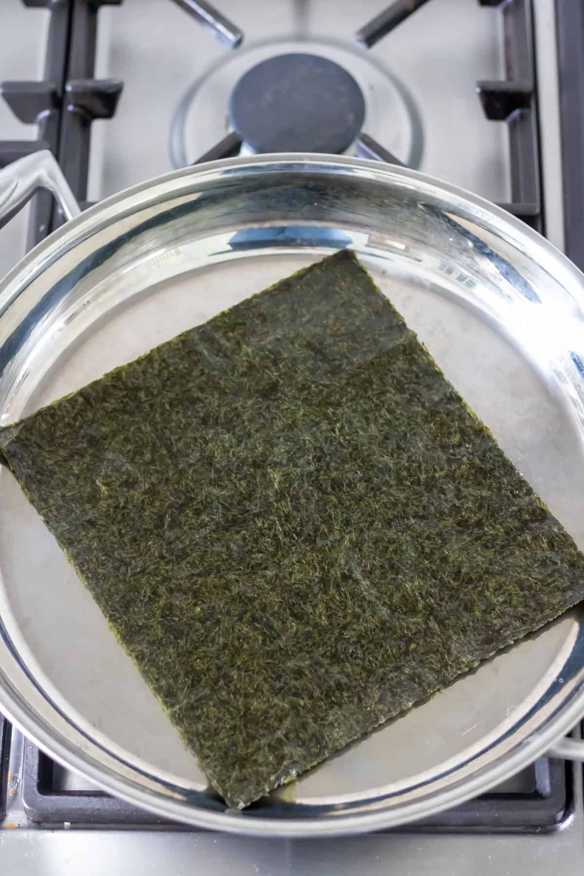 Toasting nori seaweed in a skillet.