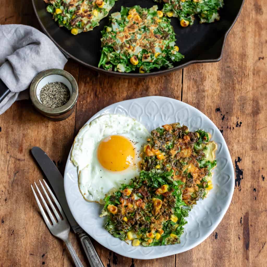 Looking down at a plate of kale fritters and a fried egg.